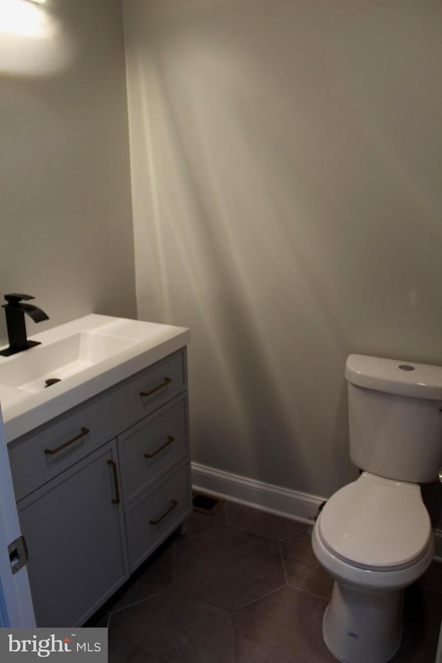 bathroom featuring toilet, tile patterned flooring, vanity, and baseboards