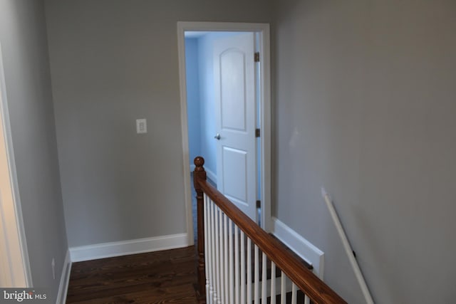 hall featuring wood finished floors, an upstairs landing, and baseboards