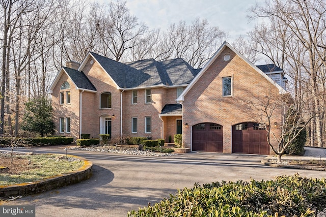 view of front of house featuring driveway, an attached garage, and brick siding