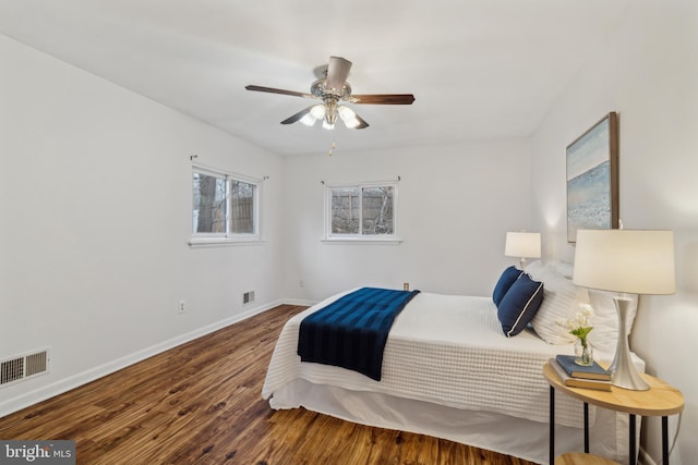 bedroom featuring visible vents, ceiling fan, baseboards, and wood finished floors