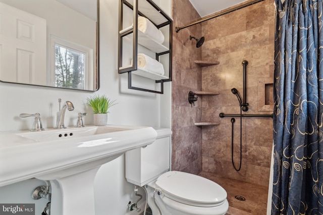 bathroom with a sink, a tile shower, and toilet