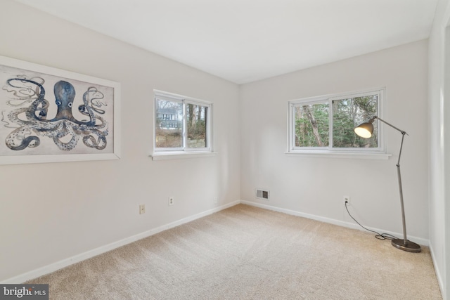 empty room featuring carpet, visible vents, and baseboards