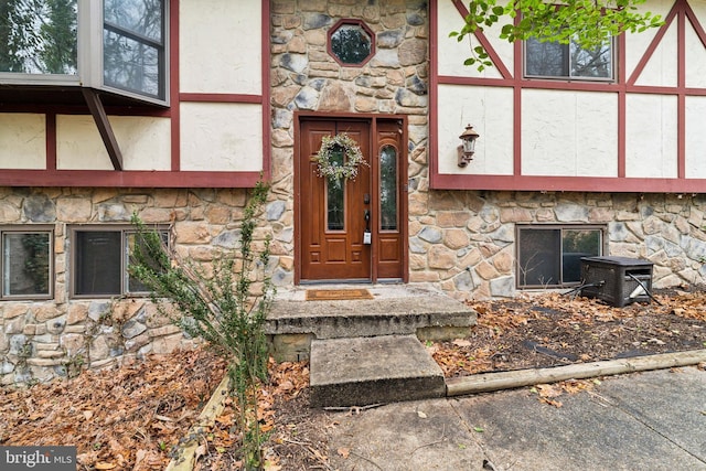 entrance to property featuring stone siding and stucco siding