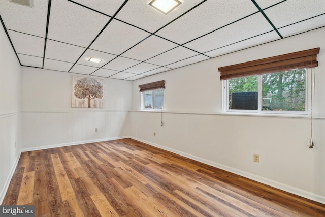 unfurnished room with a paneled ceiling, plenty of natural light, baseboards, and wood finished floors