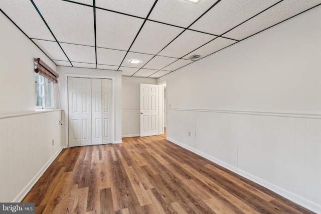 unfurnished bedroom featuring a closet, a drop ceiling, and wood finished floors