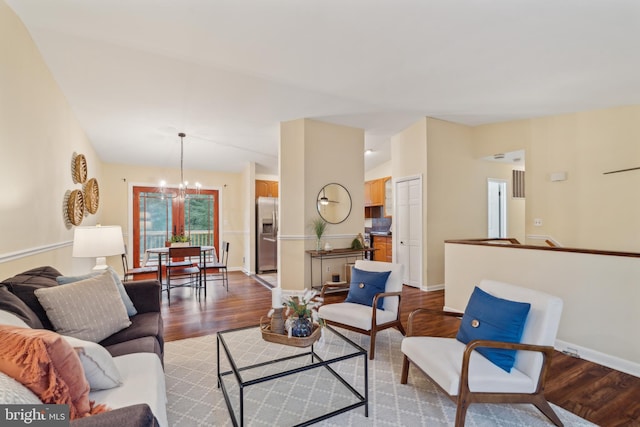 living area with an inviting chandelier, baseboards, and wood finished floors