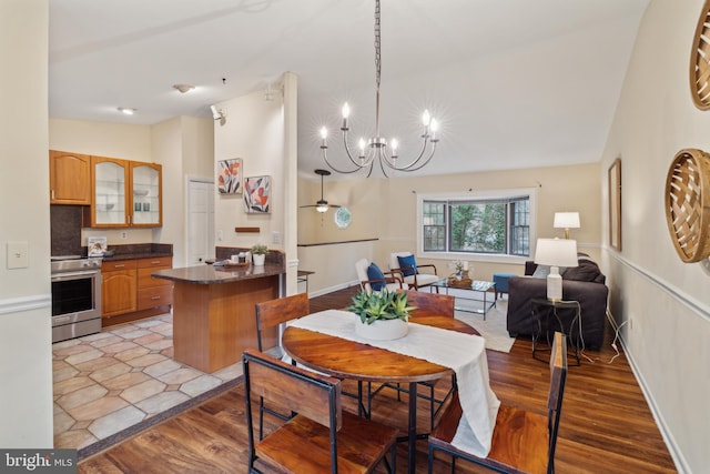 dining room with vaulted ceiling, light wood finished floors, baseboards, and a notable chandelier