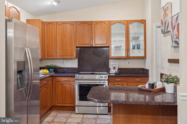 kitchen with vaulted ceiling, stainless steel appliances, light tile patterned floors, and glass insert cabinets