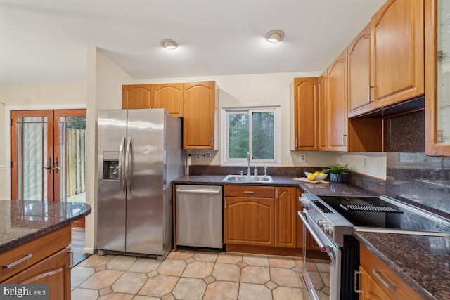 kitchen with light tile patterned floors, dark stone countertops, stainless steel appliances, french doors, and a sink