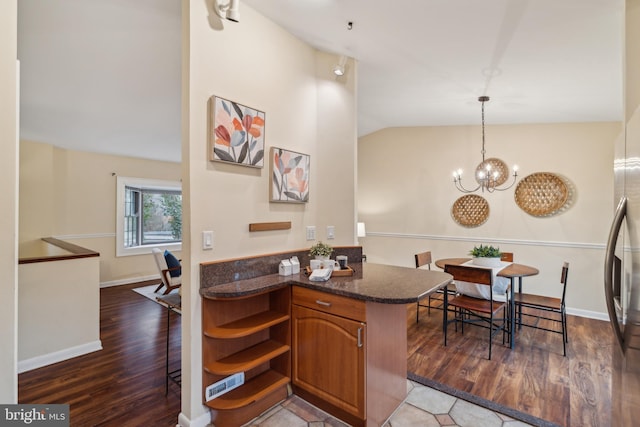 kitchen featuring brown cabinets, a notable chandelier, open shelves, vaulted ceiling, and wood finished floors