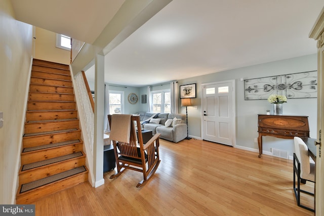 interior space with stairway, light wood-type flooring, visible vents, and baseboards