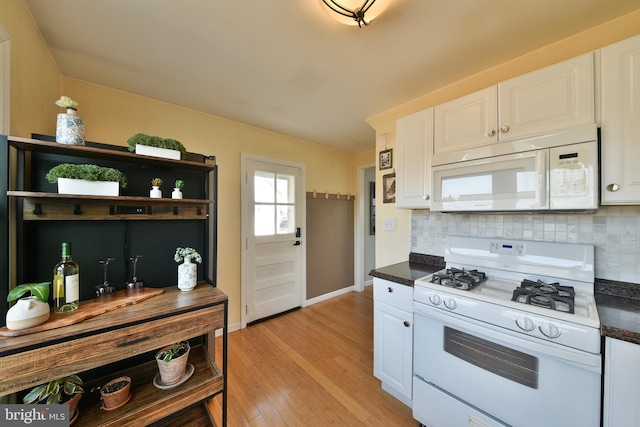 kitchen with white appliances, dark countertops, backsplash, and white cabinetry