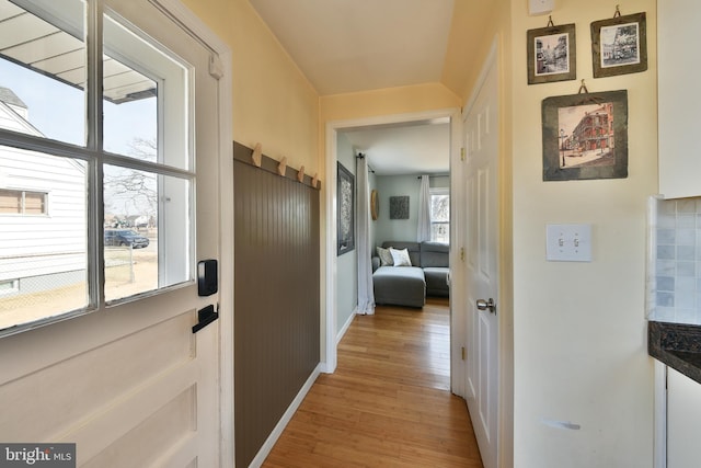 hallway featuring light wood finished floors and baseboards