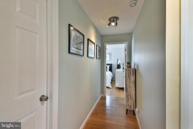 corridor with light wood-type flooring and baseboards