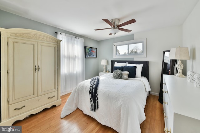 bedroom featuring ceiling fan, multiple windows, and light wood-style flooring