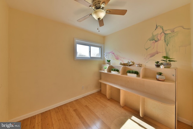 interior space with light wood finished floors, baseboards, and a ceiling fan