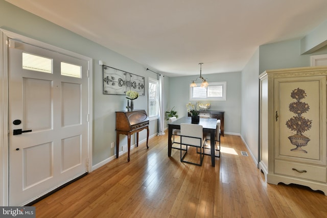 dining room featuring baseboards, a notable chandelier, visible vents, and light wood-style floors