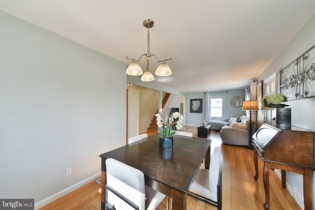 dining space featuring stairway, light wood-style flooring, and baseboards