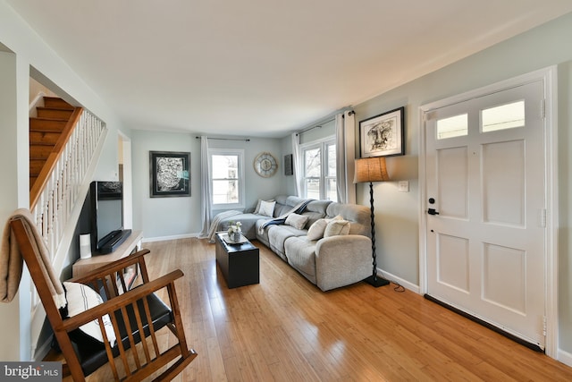 living area featuring light wood-style floors, stairway, and baseboards