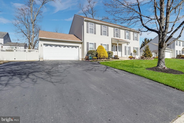 colonial house featuring aphalt driveway, a front yard, fence, and an attached garage