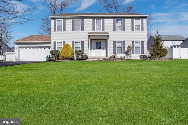 colonial inspired home featuring driveway, an attached garage, fence, and a front yard