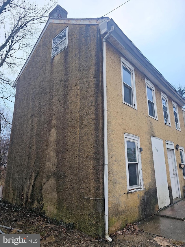 view of side of home with stucco siding and a chimney