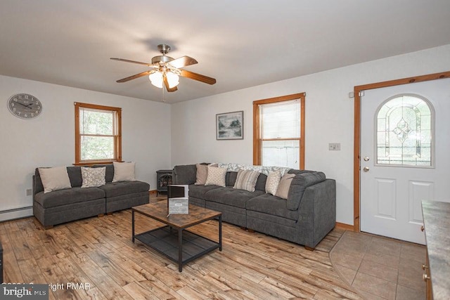 living room featuring a baseboard heating unit, a ceiling fan, and light wood-style floors