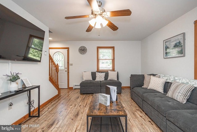 living area featuring a baseboard radiator, ceiling fan, wood finished floors, baseboards, and stairs