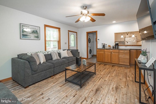 living room featuring light wood finished floors, recessed lighting, a ceiling fan, stacked washing maching and dryer, and baseboards