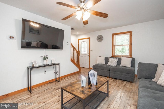 living room featuring a ceiling fan, baseboards, stairway, and wood finished floors