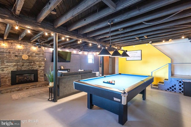 rec room featuring billiards, concrete flooring, and a stone fireplace