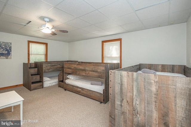 carpeted bedroom featuring baseboards, a ceiling fan, and a drop ceiling