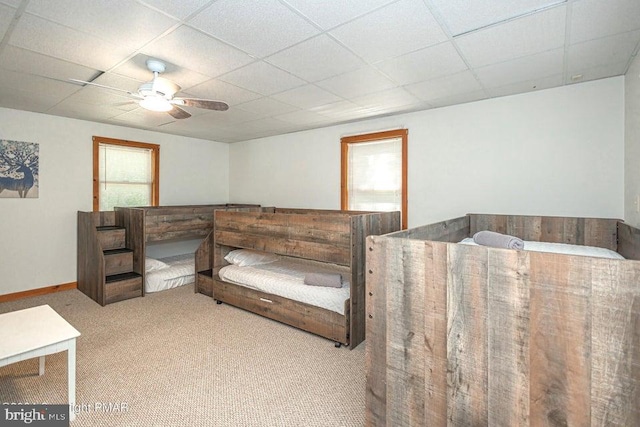 bedroom featuring baseboards, carpet, a ceiling fan, and a drop ceiling