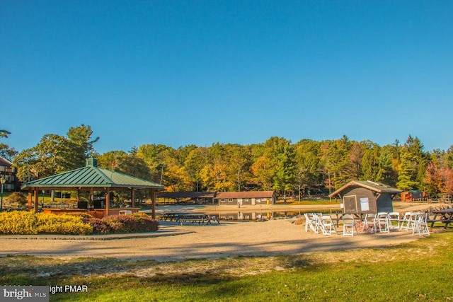 view of property's community featuring a yard, a view of trees, and a gazebo