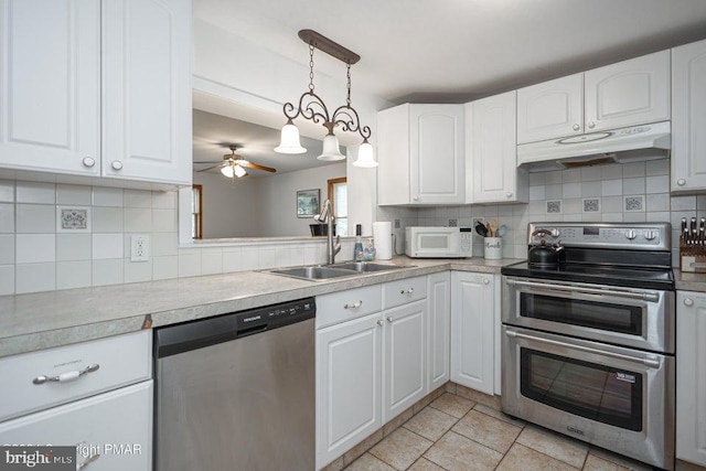 kitchen featuring stainless steel appliances, under cabinet range hood, and decorative backsplash