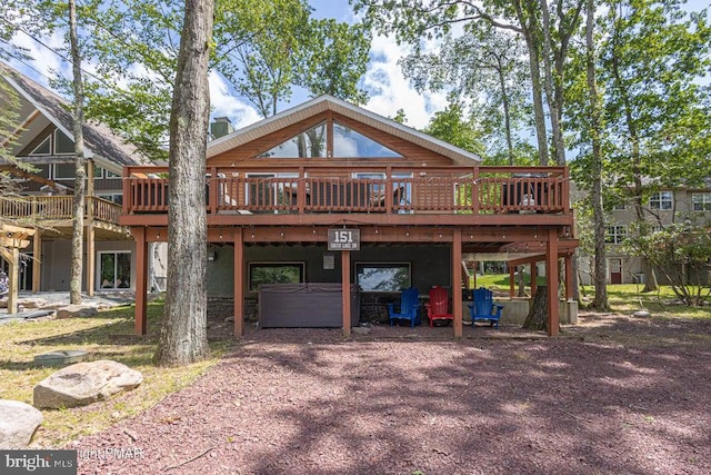 back of property featuring a jacuzzi and a deck