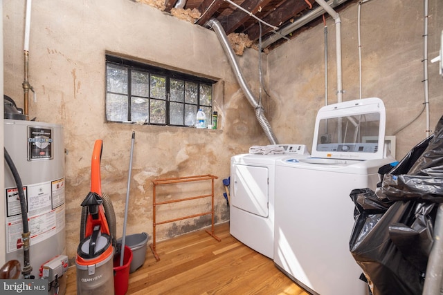 laundry room featuring wood finished floors, washing machine and dryer, water heater, and laundry area