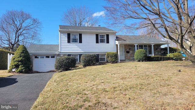 tri-level home featuring aphalt driveway, stone siding, a garage, and a front yard