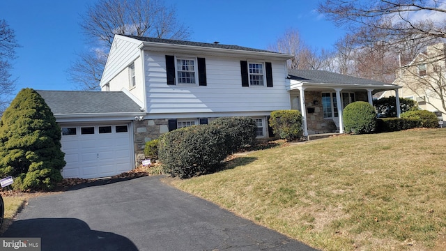 split level home with driveway, an attached garage, a shingled roof, a front lawn, and stone siding