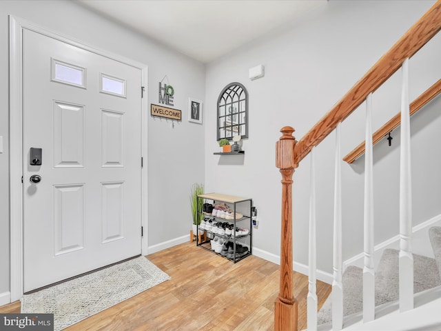 foyer entrance with stairs, light wood finished floors, and baseboards