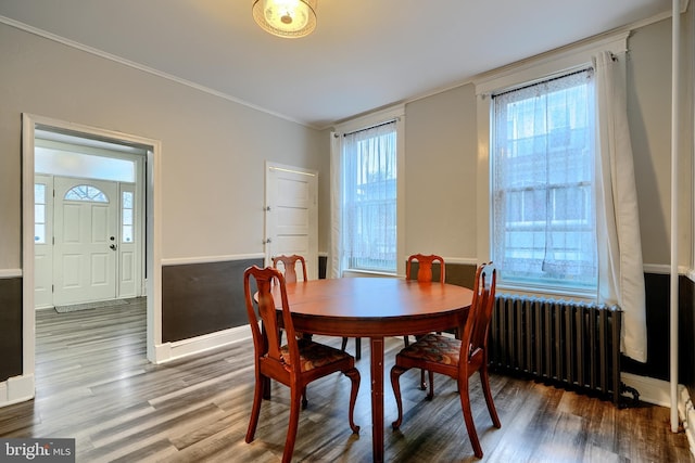 dining area featuring baseboards, crown molding, radiator heating unit, and wood finished floors