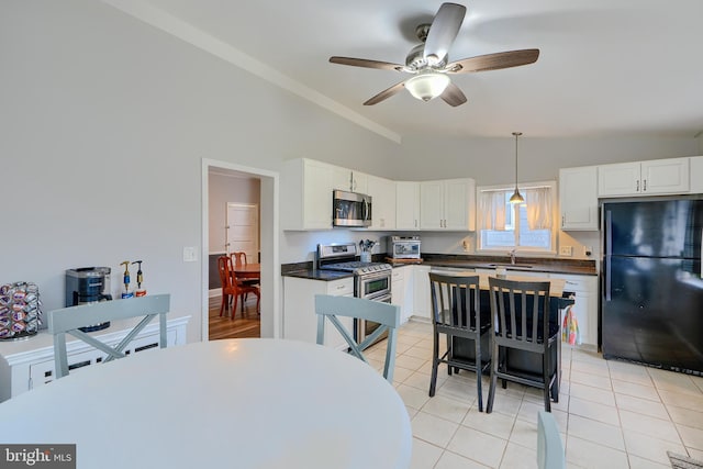 kitchen featuring appliances with stainless steel finishes, dark countertops, vaulted ceiling, and light tile patterned floors