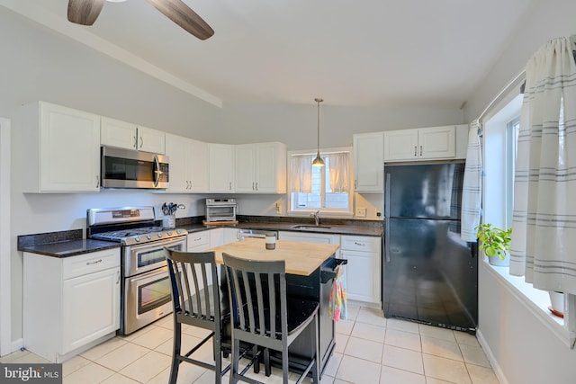 kitchen with appliances with stainless steel finishes, lofted ceiling, white cabinetry, and a sink