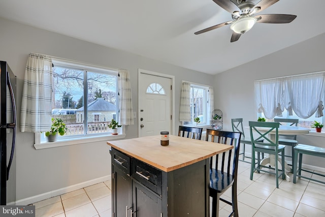 kitchen with light tile patterned floors, plenty of natural light, a kitchen bar, and wooden counters