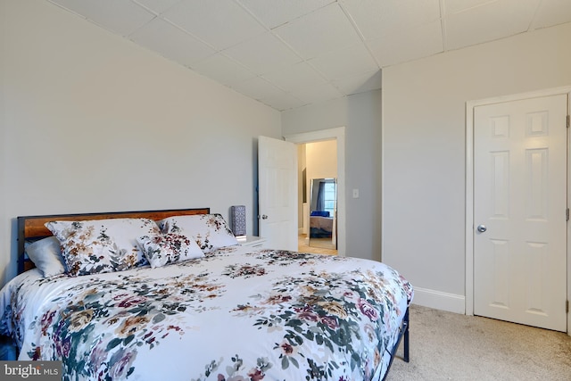 bedroom with baseboards, a paneled ceiling, and light colored carpet