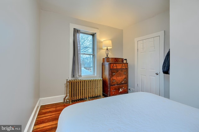 bedroom featuring baseboards, radiator heating unit, and wood finished floors