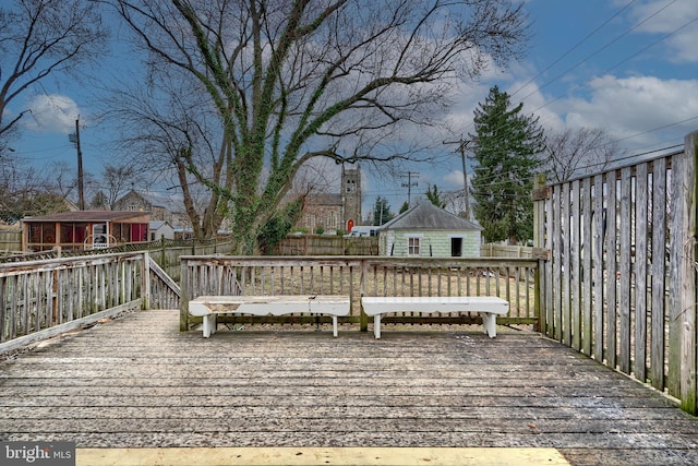 wooden terrace featuring fence and an outdoor structure