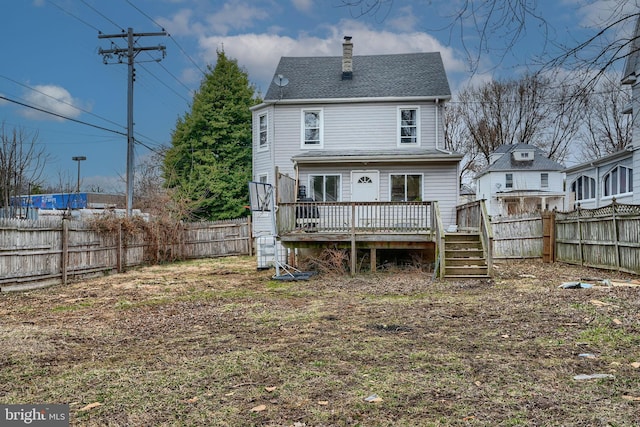 back of property with a fenced backyard, a chimney, and a deck