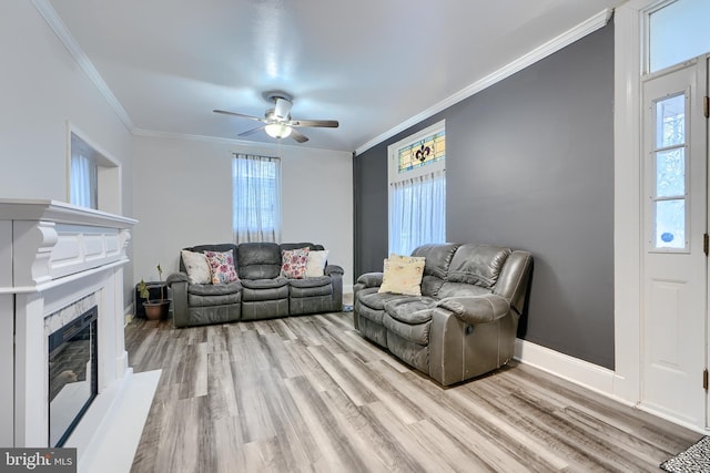 living area featuring light wood-style floors, a healthy amount of sunlight, and crown molding