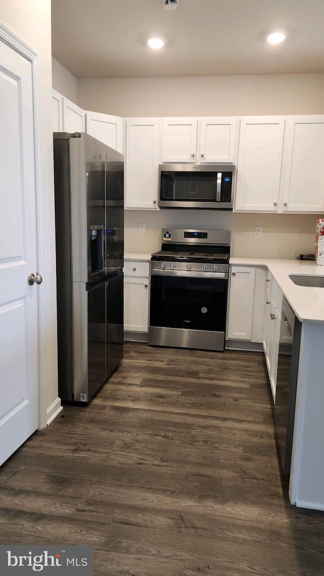 kitchen featuring stainless steel appliances, dark wood-style flooring, and white cabinets